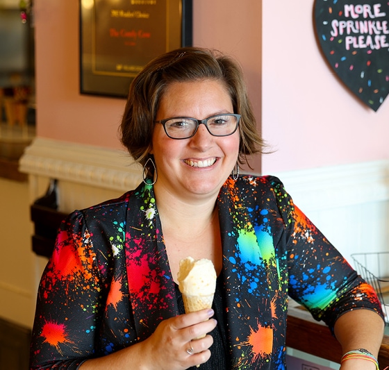 Grant writing professional Bethany Planton smiles while wearing a brightly colored blazer and holding an ice cream cone.