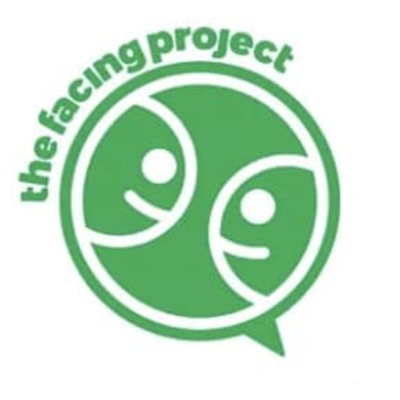 Logo for The Facing Project: Two faces smile at each other inside of a green circle, with green logo text on the upper left outside of the circle.
